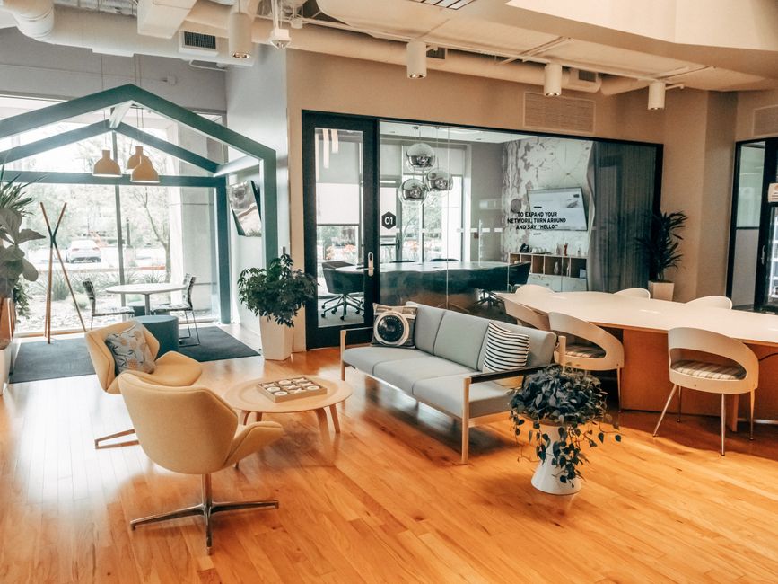 A stylish open office space featuring modern furniture with a relaxed lounge area and glass partitions.